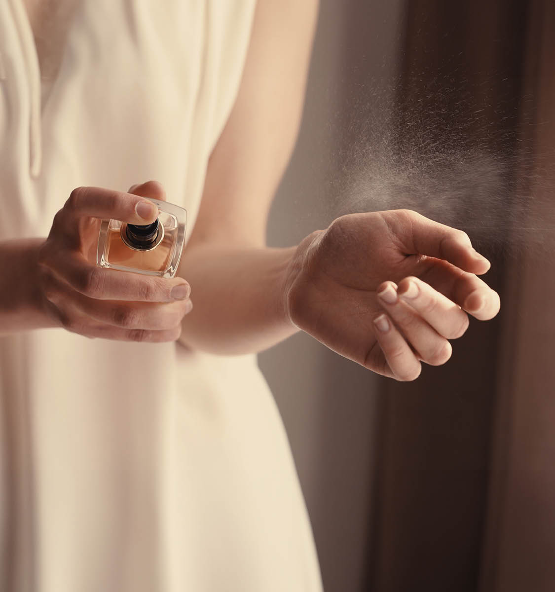 Beautiful young woman with bottle of perfume at home, closeup